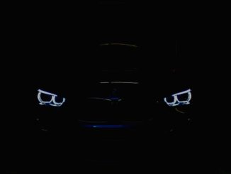 black car in the dark with lighted daytime running lights
